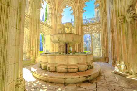 Batalha, Portugal - August 16, 2017: glow that filters through the arches surrounding the lavatory or famous fountain of Mateus Fernandes at Monastery of Batalha, in Portugal.のeditorial素材
