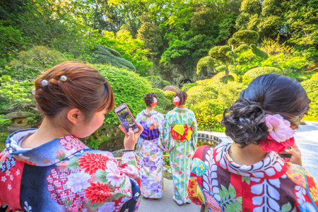 Kamakura, Japan - April 23, 2017: four young women wearing traditional kimono take photo with smartphone at japanese zen garden inside Take-dera or Hokoku-ji Temple in Kamakura. Japanese lifestyle.のeditorial素材