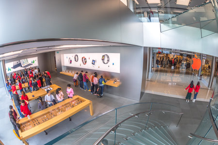 Hong Kong, China - December 4, 2016: fish-eye aerial view of Apple store of IFC Mall, with customers looking the new technological products and shop clerks in red.のeditorial素材