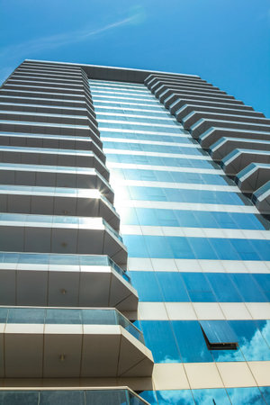 Dubai, UAE - May 1, 2013: vertical of modern shiny blue glass facade of high rise building in...