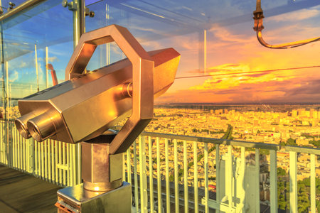 Paris, France - June 30, 2017: details of look-out binoculars with view above urban cityscape skyline of Paris at colorful sunset from Tour Montparnasse Observation Deck.のeditorial素材