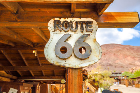 Closeup of Route 66 sign at Calico Ghost Town in blurred background. Mining town in Calico Mountains...