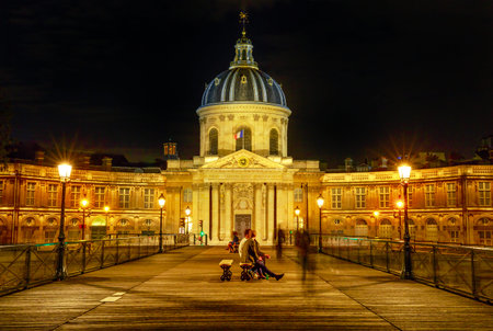Paris, France - July 1, 2017:Pont des Arts bridge to Institut de France building, a French learned society group of five academies. Crossing bridge point of view with people in Paris, France. Night scene.のeditorial素材