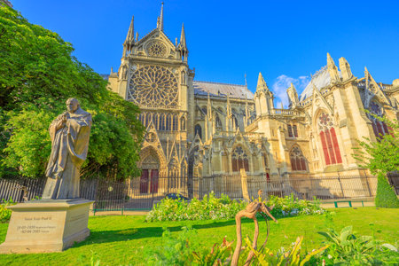 Paris, France - July 1, 2017: Pope John Paul II statue on side of church Notre Dame of Paris, France. Gothic architecture of Cathedral of Paris, Ile de la cite. Beautiful sunny day in the blue sky.のeditorial素材