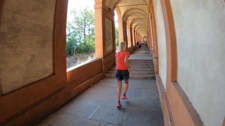 A sporty woman running under San Lucas portico: the longest porch in the world leading to the San...