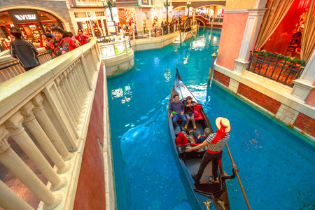 Macau, China - December 9, 2016: gondolier singing italian songs for tourists in a romantic ride on an real gondola boat on Grand Canal of Shoppes at the Venetian Luxury Hotel and Casino.のeditorial素材