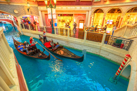 Macau, China - December 9, 2016: gondoliers with tourists on a ride by gondola on the Grand Canal of the Venetian Casino. In luxury shopping mall in the Venetian Hotel, Cotai Strip.のeditorial素材