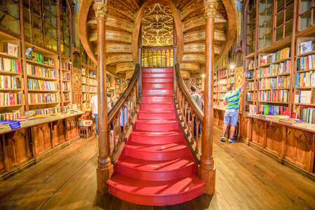 Oporto, Portugal - August 13, 2017: large wooden staircase with red steps inside Library Lello and Irmao in historic center of Porto, famous for Harry Potter film. Horizontal shot.のeditorial素材
