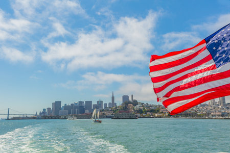 San Francisco, California, United States - August 14, 2016: Alcatraz tour to Alcatraz island by boat trip in San Francisco Bay. Ferry boat and American flag waving in San Francisco pier with cityscapeのeditorial素材