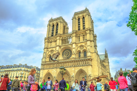 Paris, France - July 1, 2017: tourists enjoy the pigeons feeding in Notre Dame square. in Paris. Popular tourist destination in French capital. The Cathedral on background.のeditorial素材