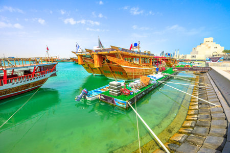 Doha, Qatar - February 16, 2019: many wooden dhows docked at beginning of Dhow Harbor with Museum of...