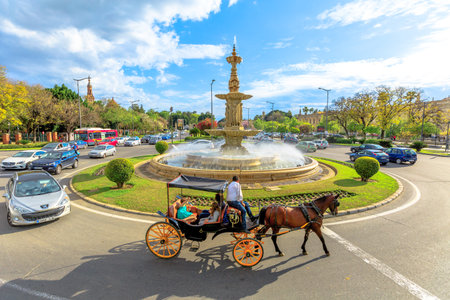 Seville, Andalusia, Spain - April 19, 2016: City sightseeing of horse carriage ride around fountain in Plaza Don Juan de Austria. Urban cityscape from Hop-On Hop-Off Touristic Bus in a sunny day.のeditorial素材
