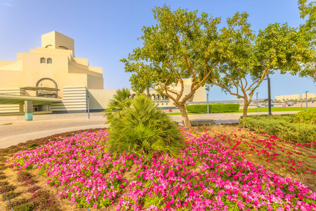 Flower beds and blooming trees along seafront of Doha Bay in Doha park. Popular tourist attraction...