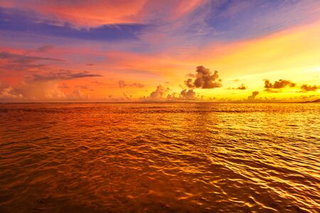 Seychelles, La Digue, Anse Source d'Argent at twilight. Landscape of colorful clouds in the sky on rock stone of granite boulder. Calm and tranquil sea on the horizon.の写真素材