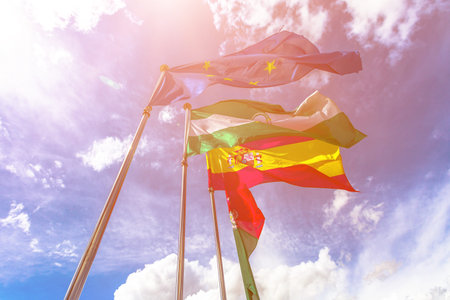 Flags of Europe, Andalusia, Granada and Spain, waving in a cloudy sky. Free sky background for copy...