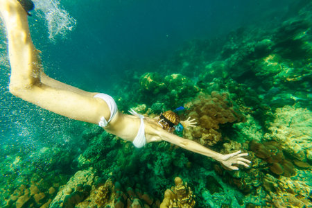 side view of snorkeling girl in apnea swimming in Surin Islands, Andaman Sea, North of Phuket, Phang...