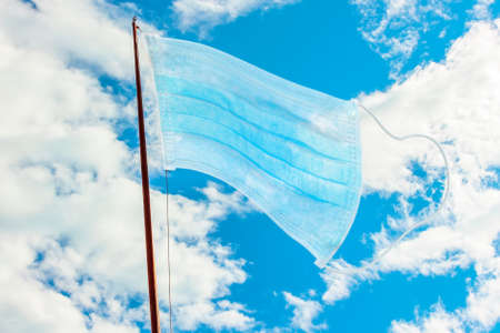 flag of surgical mask on a blue cloudy sky. Concept of outbreak and quarantine for COVID-19 coronavirus pandemic in the world. Concept of woldwide unity against coronavirus epidemic. Coronavirus freeの写真素材
