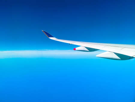 wing of an airplane during flight in a clear blue sky with copy space.の写真素材