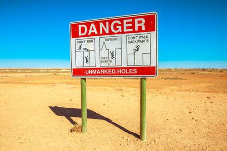 Danger road sign for unmarked holes in Coober Pedy underground town in Australia. Opal mining town in the South Australian outback desert.の写真素材