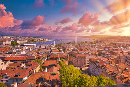 Amazing dramatic sky with red clouds of sunset over Geneva skyline cityscape, French-Swiss in Switzerland. Aerial view of Jet deau fountain, Lake Leman, bay and harbor from Saint-Pierre Cathedral.の写真素材