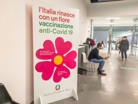 Bologna, Italy - April 2021: people with surgical masks in the queue inside the Italian vaccination center to get vaccinated with the new vaccine. Italian poster of the vaccination campaign in Europe.のeditorial素材