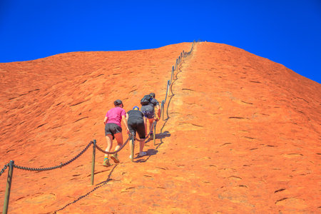 Uluru, Northern Territory, Australia - Aug 23, 2019: Climbers ascend Uluru in Kata Tjuta National Park against the wishes of the aboriginal people Anangu land owners.のeditorial素材