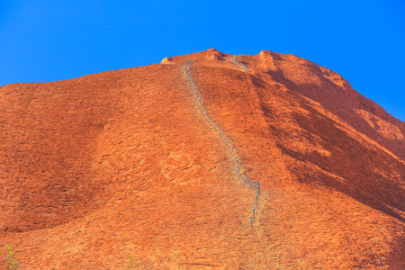 Uluru, Northern Territory, Australia - Aug 26, 2019: safety chain, 138 steel posts, painted guidelines along Ayers Rock in Uluru-Kata Tjuta National Park. The October, 26, 2019 the climb will be closedのeditorial素材