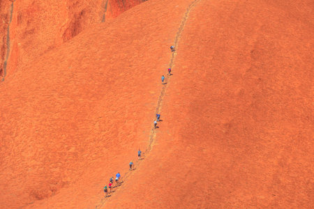 Uluru, Northern Territory, Australia - Aug 26, 2019: people climb on Ayers Rock. Climbing Uluru is sacred to Anangu people, the traditional owners of Uluru-Kata Tjuta and very dangerous.のeditorial素材