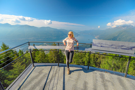 Woman on Aussichtsplattform Cardada platform on top of Cardada-Cimetta mount in Switzerland. Skyline from Swiss cable car of Locarno on Cardada mount. Lake Langensee cityscape in Ticino.の写真素材