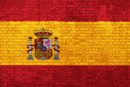Wall of bricks painted with the flag of Spain, red and yellow colors. 3d background. Concept of social barriers of immigration, divisions, and political conflicts in Spain.の写真素材