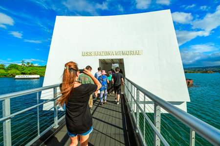 HONOLULU, OAHU, HAWAII, UNITED STATES - AUGUST 21, 2016: Tourists at the monument in honor of the USS Arizona BB-39 shipwreck of world war 2 in Pearl Harbor, with the American flag in memorial.のeditorial素材
