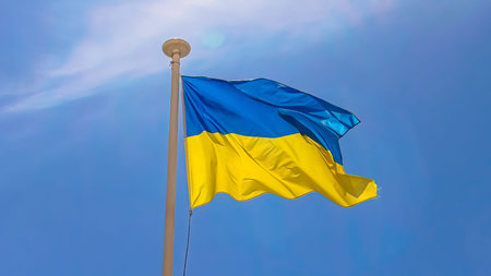 The flag of Ukraine in the wind waving isolated on blue sky background.