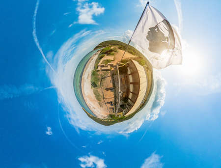 Tiny Planet of the national waving flag of Corsica island in France. Aerial view in cloudy sky of a little planet earth of Corsica island. 360 degrees panorama.の写真素材