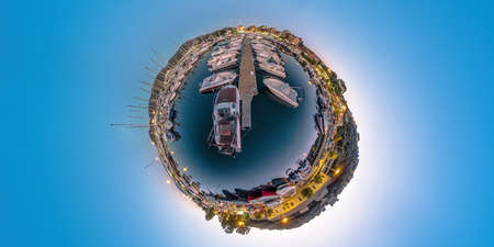 Aerial 360 tiny planet of Porto Vecchio city harbor at night in Corsica island of France. Drone view of downtown skyline with the boats and yachts in port in the Mediterranean sea after sunset.の写真素材