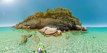 Aerial drone view of woman kayaking in the Mediterranean sea by Piana island. Top view kayak in the cliffs and cave of Petit Sperone beach, close to the Bonifacio town in Corsica of France.の写真素材