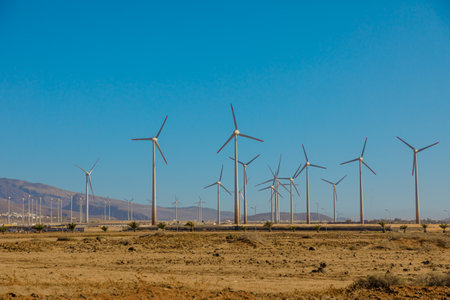 Wind turbines provide clean energy and are a sustainable solution to global warming. Panoramic view on a blue sky background is a symbol of renewable green power.の写真素材