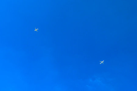 Two passenger commercial airplanes crossing flying, isolated in the blue sky. View from below ground level.の写真素材