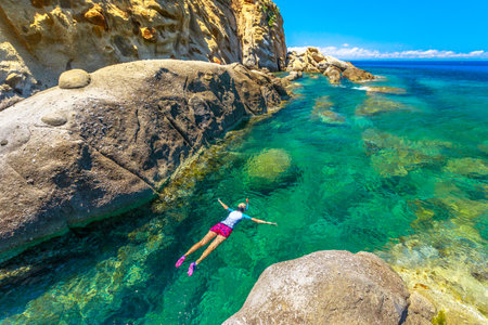 Top view of snorkeler in Sant Andrea beach Cote Piane side with rocks and coves, Elba island. Woman in clear waters of Tyrrhenian sea on holiday travel in Italy.Saint Andrew is popular seaside resortの写真素材