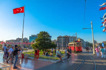 Istanbul, Turkey - Aug 2,2023: Vibrant urban life captures at taksim square with iconic red tram and turkish flagのeditorial素材