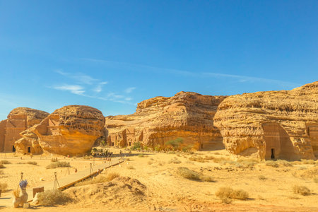 Al-Khuraymat Archaeological Site in sandstone mountains towering over the ancient city of Hegra in Al-Ula, Saudi Arabia, featuring intricate rock-cut tombs under a vibrant blue sky in the desertの写真素材