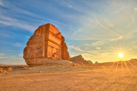 The majestic Qasr Al Farid, also known as the tomb of Lihyan son of Kuza, stands tall in the Hegra desert of AlUla, Saudi Arabia, bathed in the warm glow of the setting sunの写真素材
