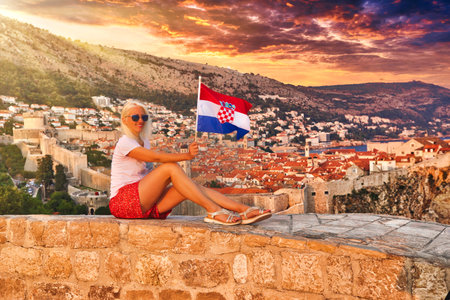 Croatian flag held by a woman on Dubrovnik fort Lovrijenac in Croatia with Fort Bokar behind. Dubrovnik is an UNESCO World Heritage Site and an old Venetian city of Croatia in Dalmatia.の写真素材