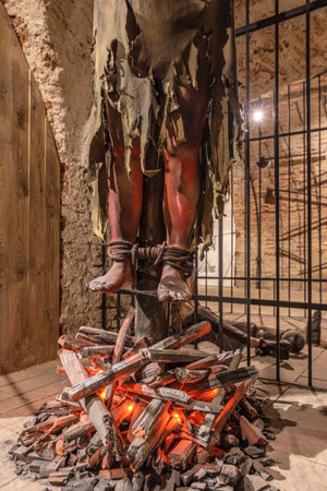 Transylvania, Romania - Oct 8, 2025: Museum display showcasing medieval torture methods, with mannequin feet tied over simulated burning wood at Corvin Castle, Hunedoara, Romaniaのeditorial素材