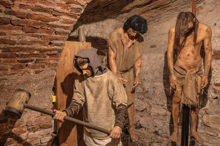 Transylvania, Romania - Oct 8, 2025: Wax figures depicting medieval torture and suffering within the historical torture chamber museum at Corvin Castle, Hunedoara, Romaniaのeditorial素材