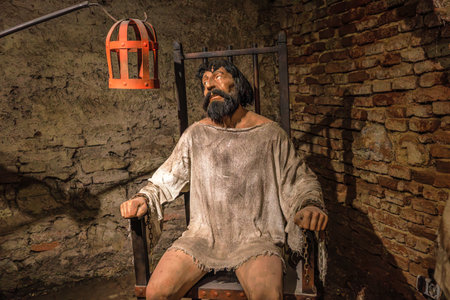Transylvania, Romania - Oct 8, 2025: Wax figures portraying medieval prisoner torture, showing a torturer holding a coercion device for a chained victim in a dark dungeon museum of Corvin Castle museumのeditorial素材