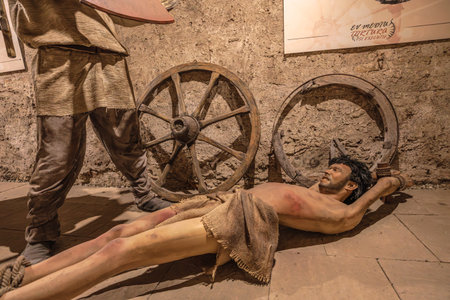 Transylvania, Romania - Oct 8, 2025: Depicting historical torture methods in a museum exhibition, showing suffering figures and ancient tools like breaking wheels of Corvin Castle museumのeditorial素材
