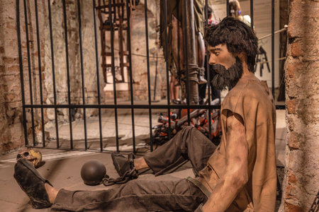 Transylvania, Romania - Oct 8, 2025: Prisoner mannequin chained inside a dark dungeon, detailing historical punishment and grim conditions from the past. Corvin Castle museumのeditorial素材