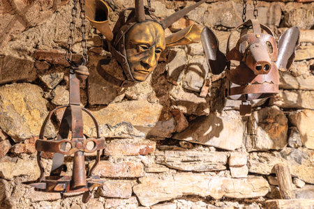 Transylvania, Romania - Oct 8, 2025: Ancient metal torture devices hanging on a rough stone wall, part of a historical exhibit in Corvin Castle, Hunedoara, Transylvania, Romaniaのeditorial素材
