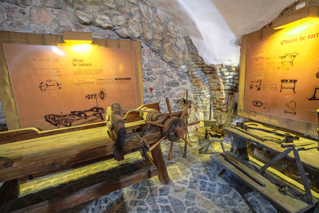 Transylvania, Romania - Oct 8, 2025: Displaying medieval torture devices and weapons inside the Corvin Castle museum, Hunedoara, Transylvania, Romania. Informative sign in Romanianのeditorial素材