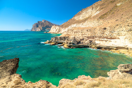 Mughsayl Beach coastline with its tranquil turquoise ocean water meeting expansive sandy shore under blue sky, viewed from a decorative balustrade terrace in Salalah, Dhofar, Oman in dry season.の写真素材